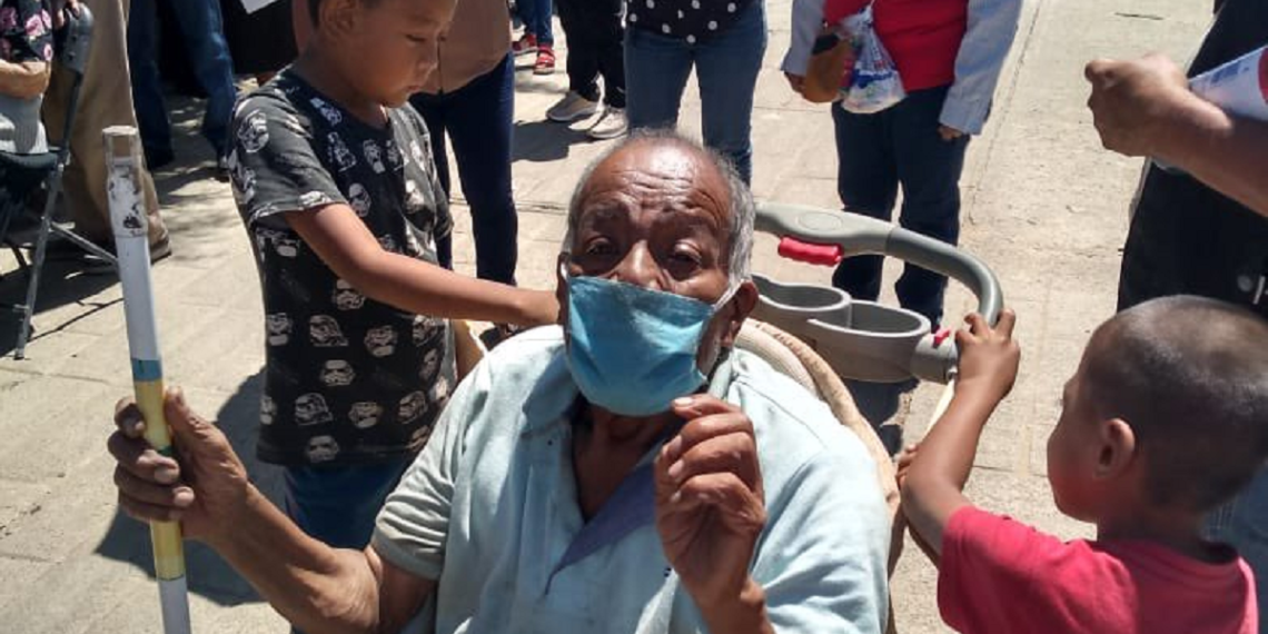 Niños llevan a su abuelito en una carriola a vacunar contra el COVID-19