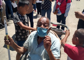 Niños llevan a su abuelito en una carriola a vacunar contra el COVID-19